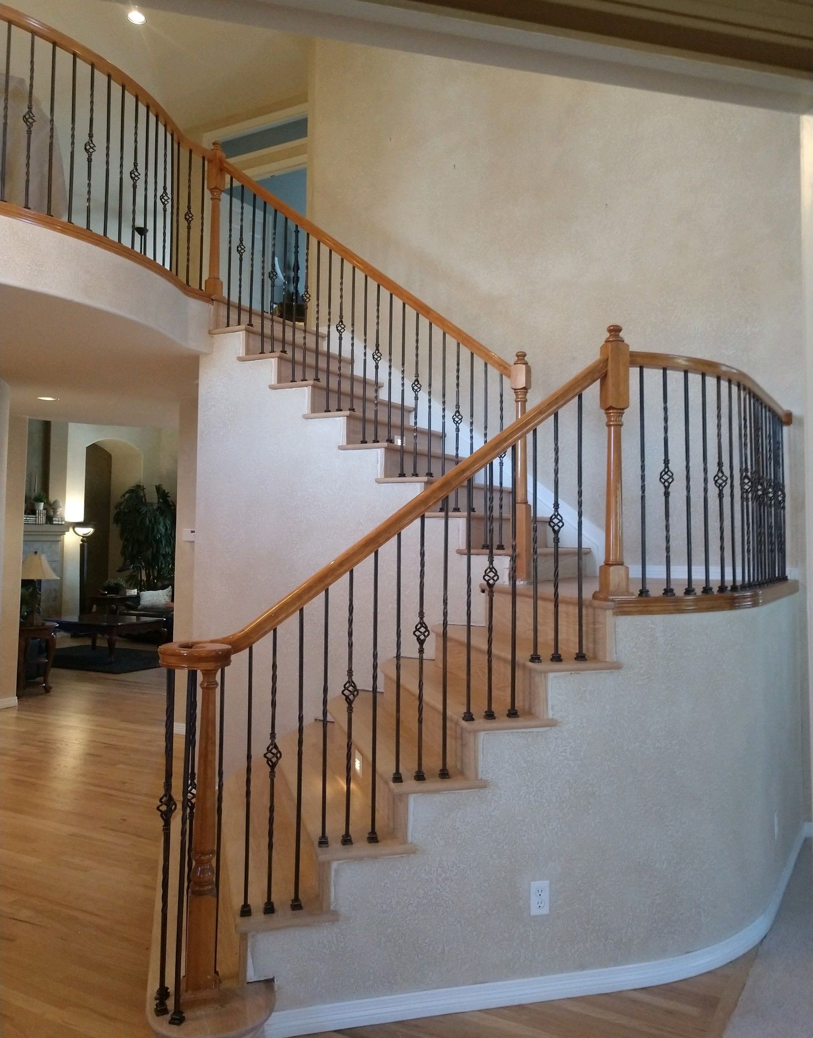 A curved staircase with a wrought iron railing
