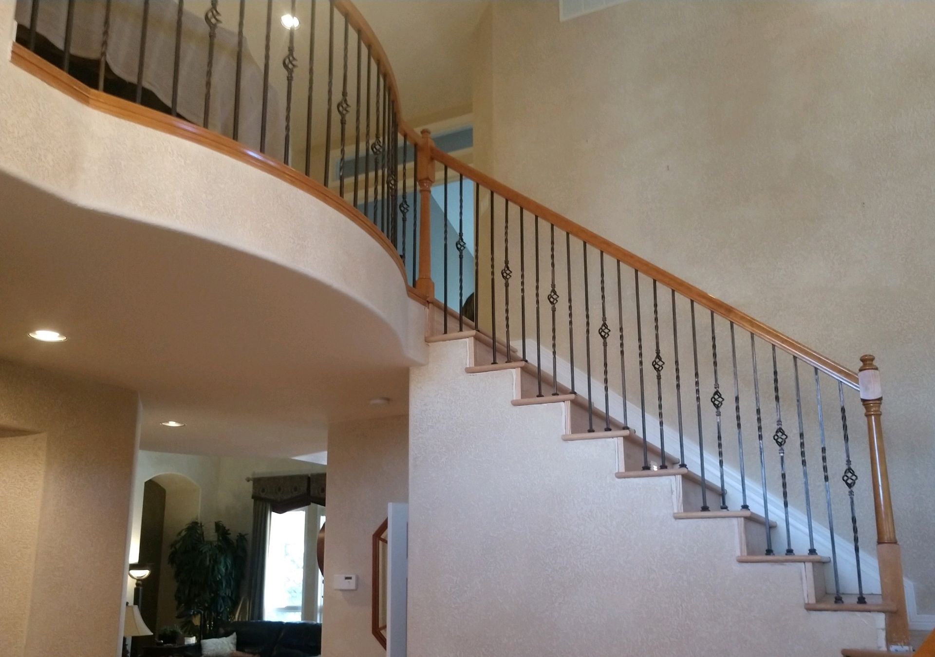 A curved staircase with a wrought iron railing