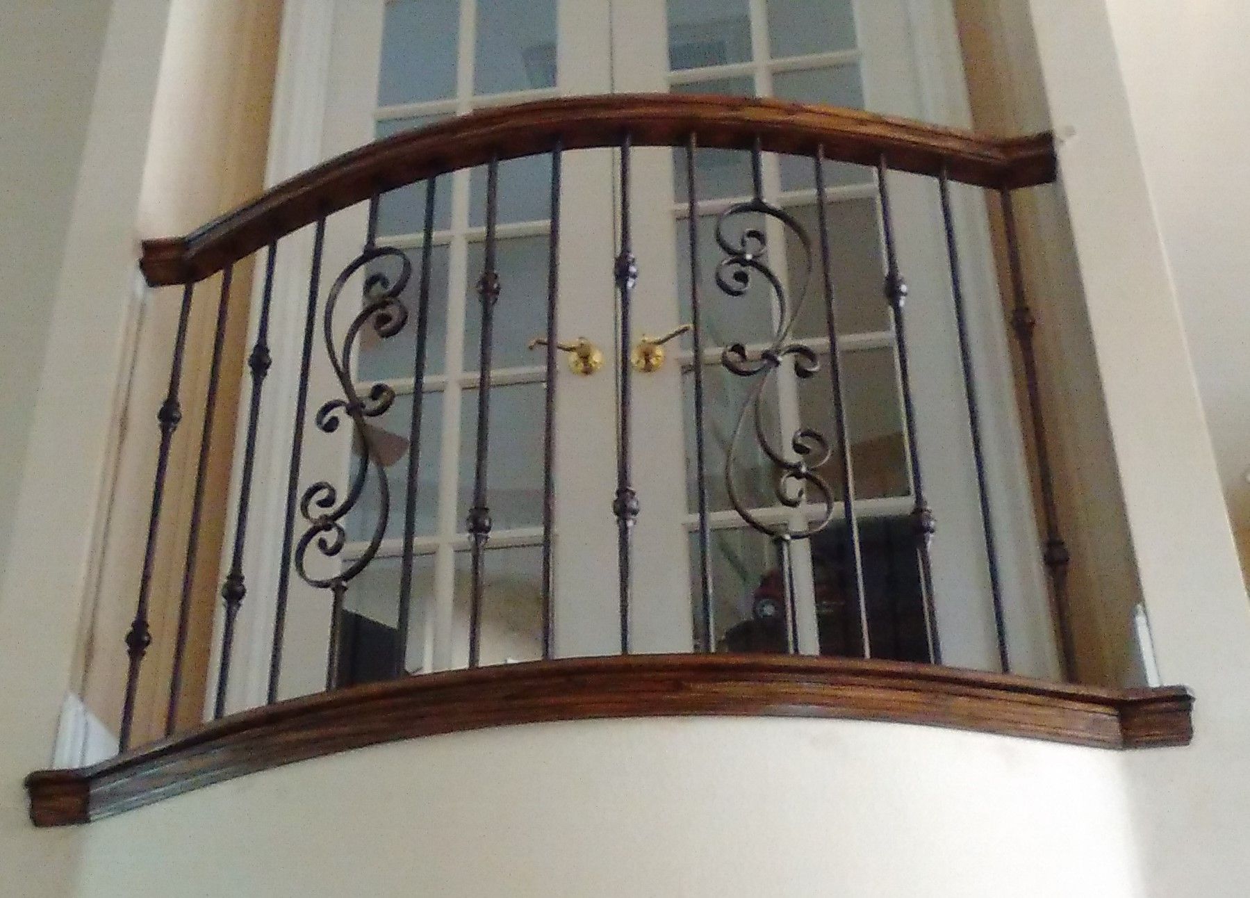 A balcony with a wrought iron railing and a wooden railing