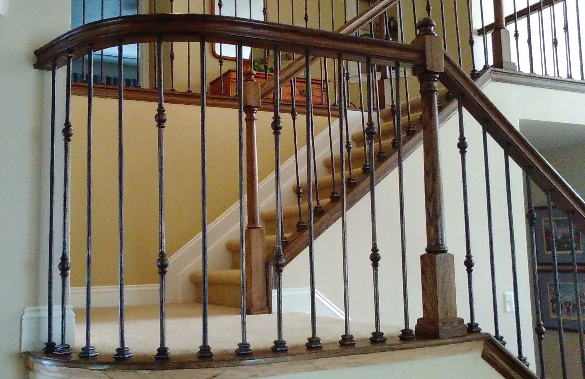 A wooden staircase with a wrought iron railing