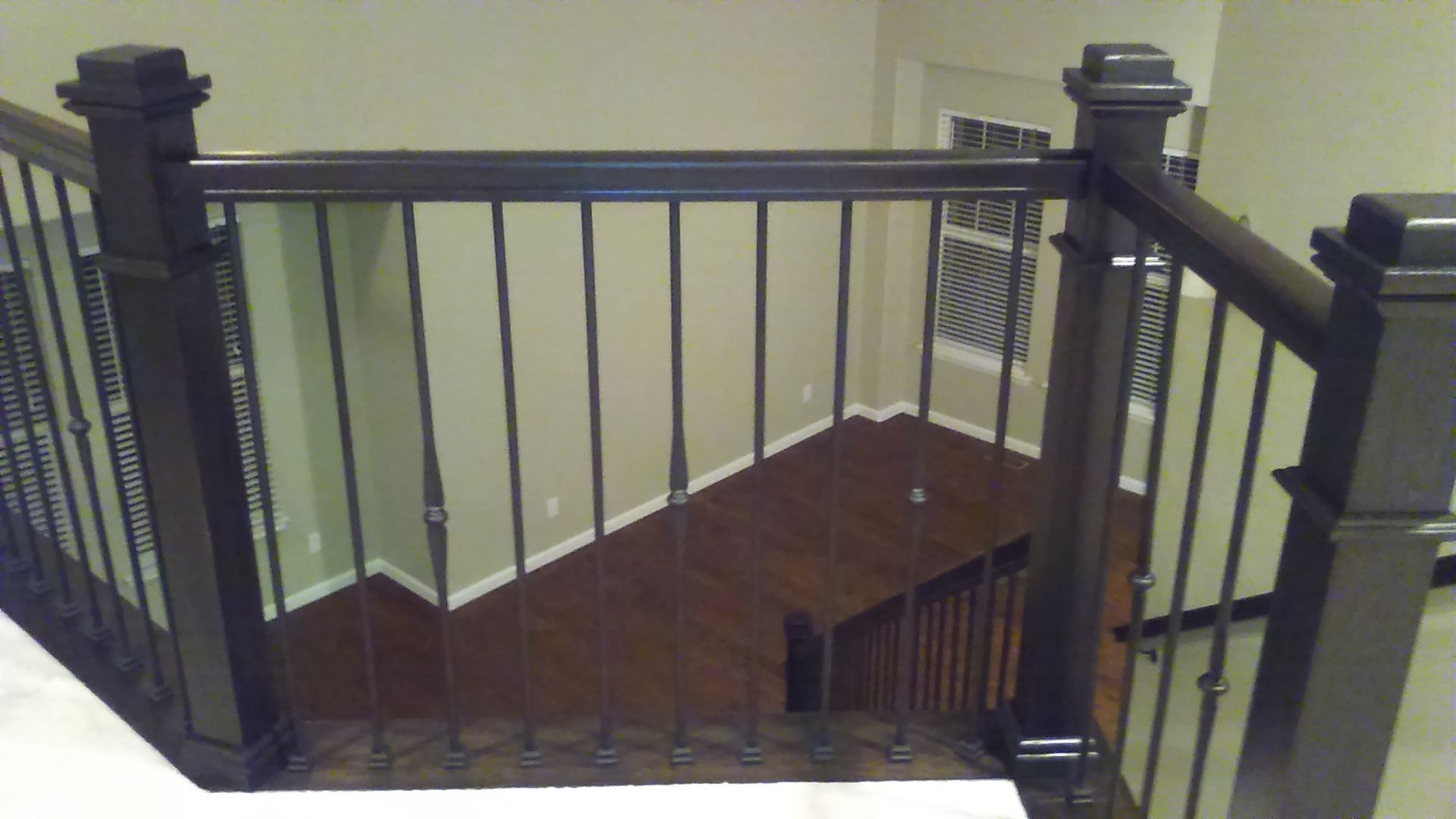 A staircase with a wrought iron railing and a wooden floor