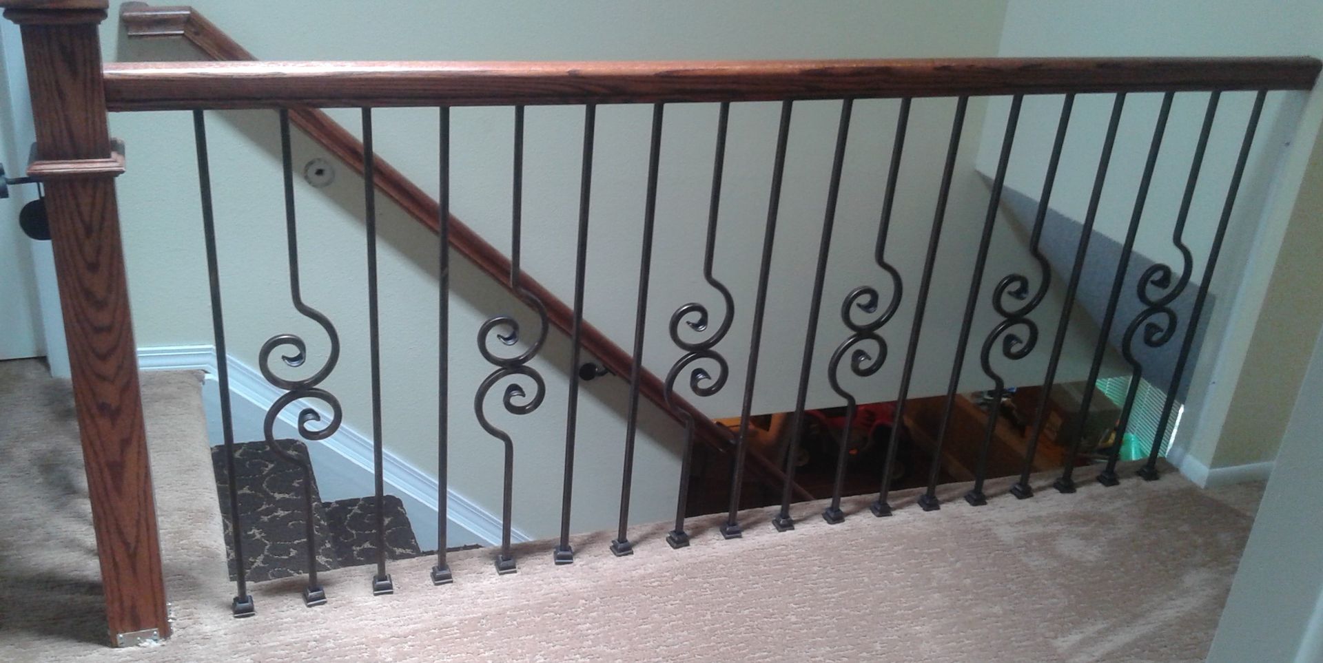 A staircase with a wrought iron railing and a wooden handrail.
