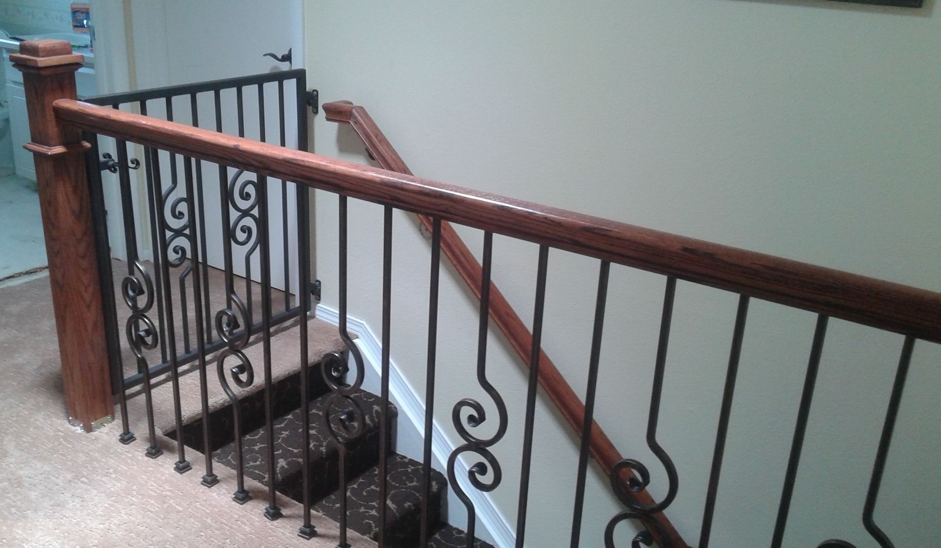 A staircase with a wrought iron railing and a wooden handrail