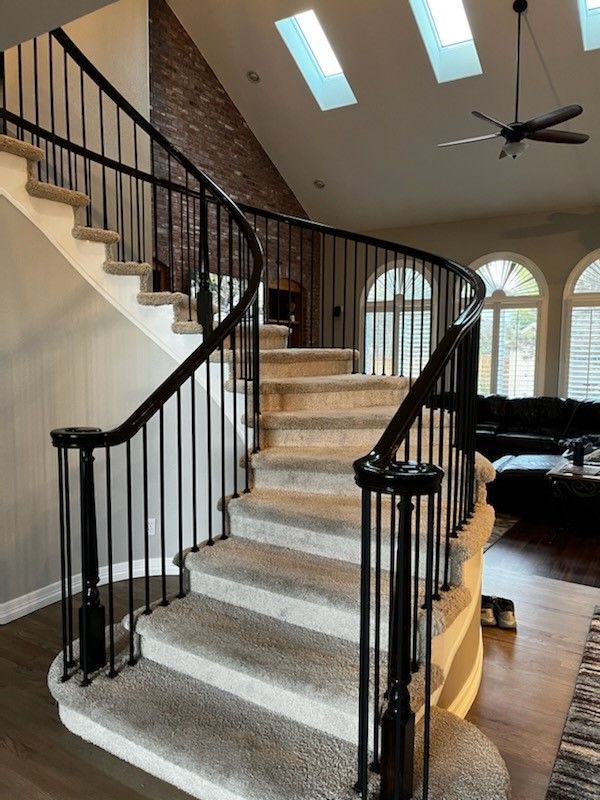 A curved staircase with a black railing in a living room.