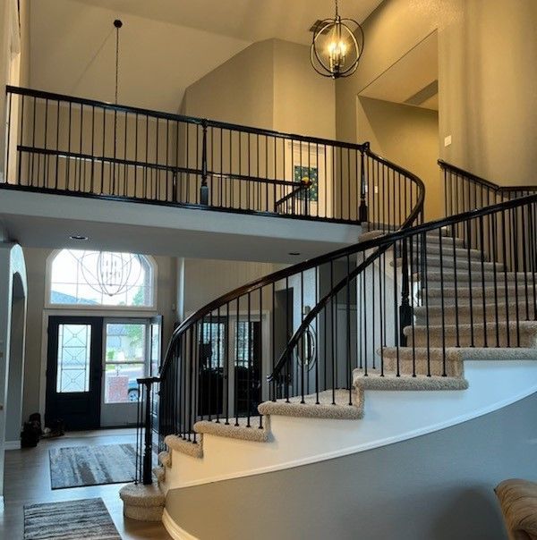 A curved staircase in a house with a black railing