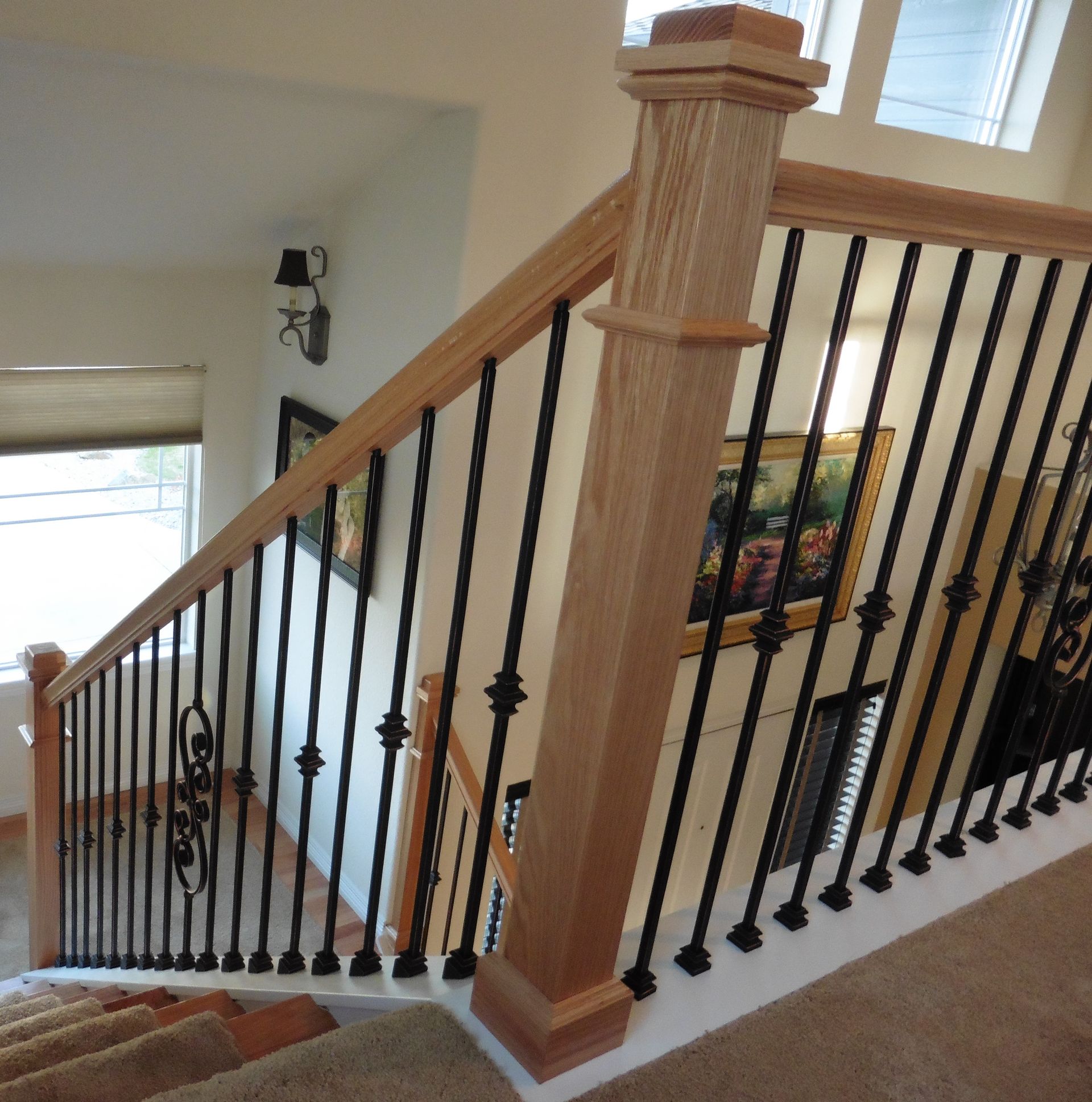 A staircase with a wrought iron railing and a wooden post
