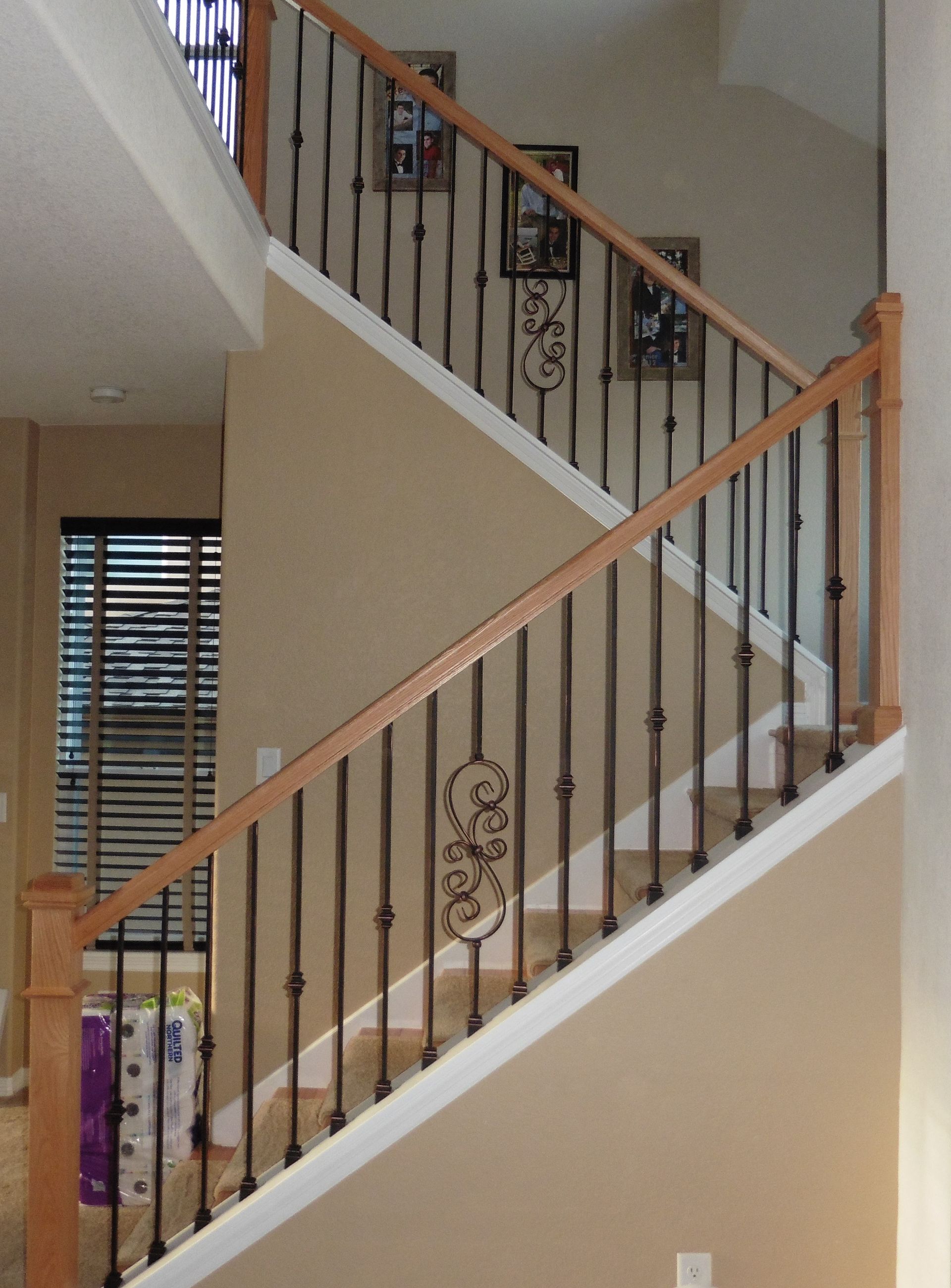 A staircase with a wrought iron railing and a wooden handrail