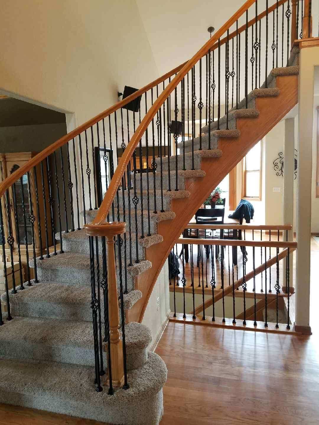 A wooden staircase with a wrought iron railing in a house.