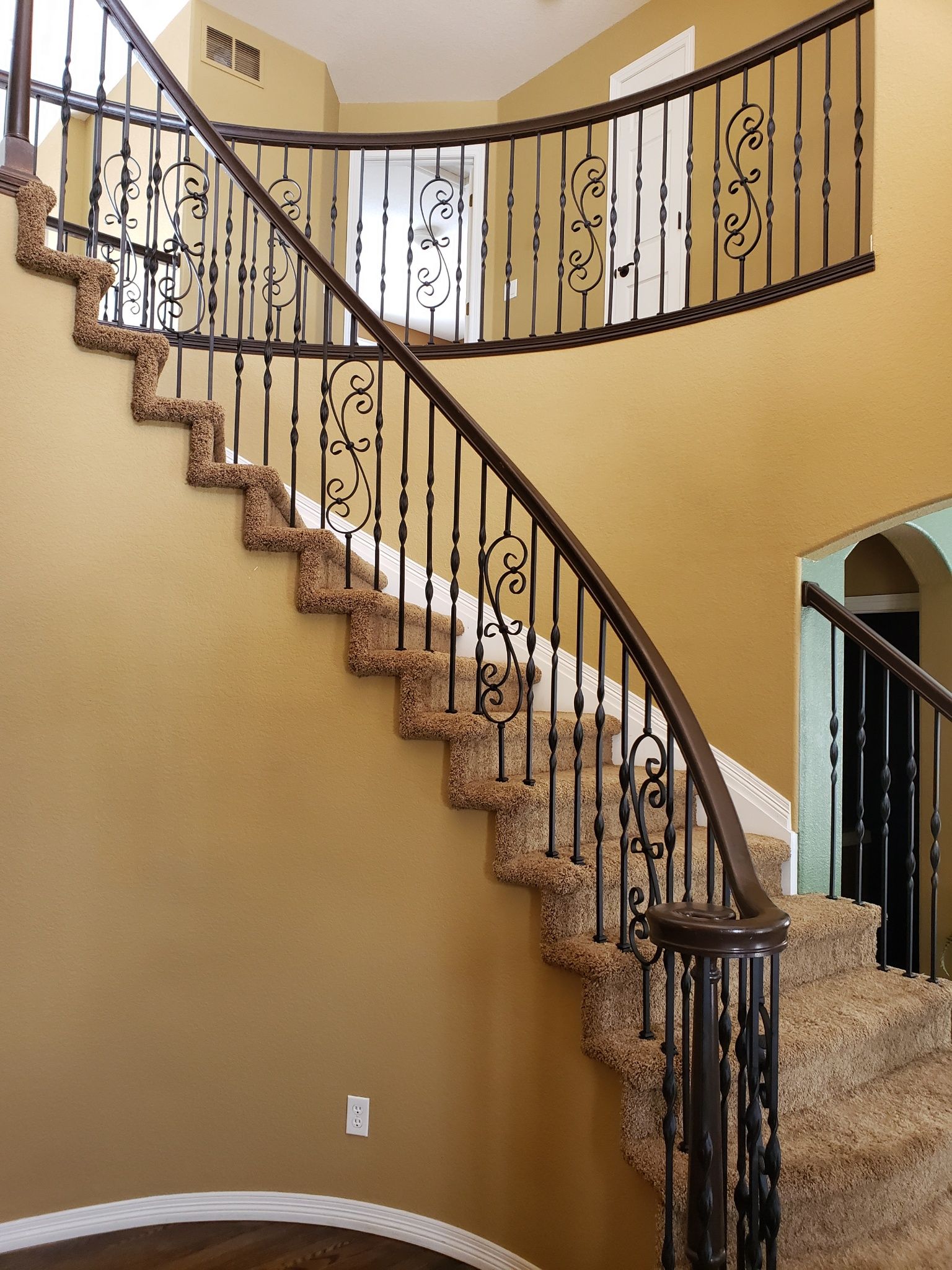 A curved staircase in a house with a wrought iron railing