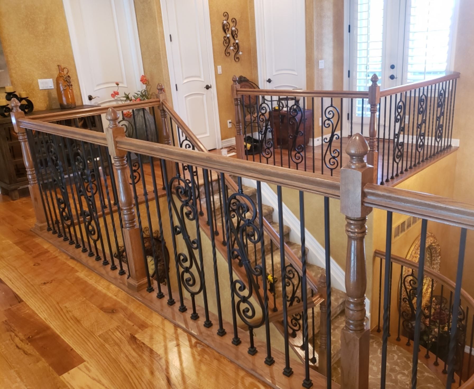 A wooden staircase with a wrought iron railing in a house.