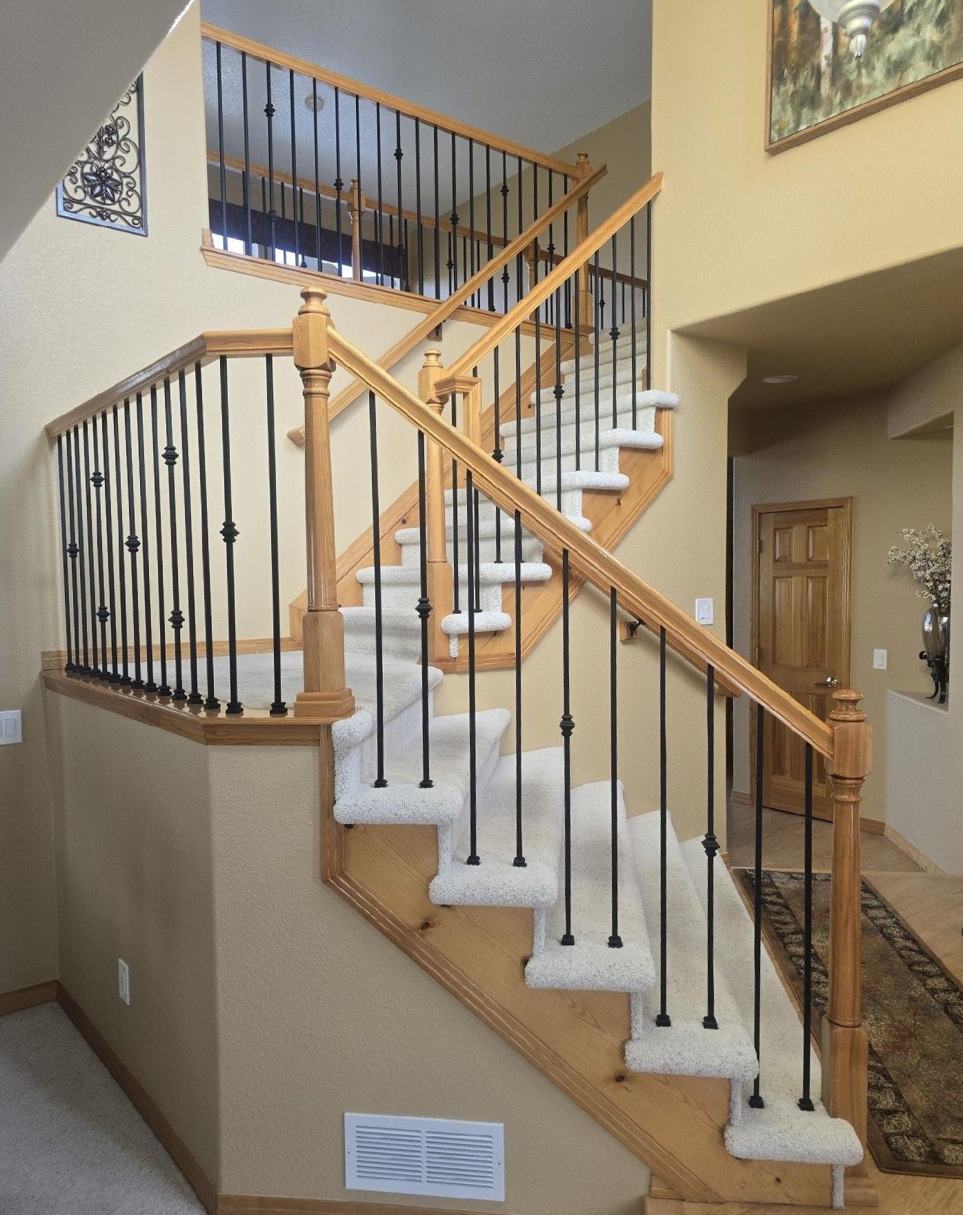A wooden staircase with a metal railing and white carpet