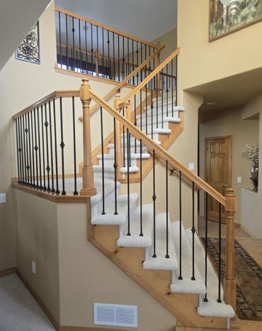 A wooden staircase with a metal railing and white carpet
