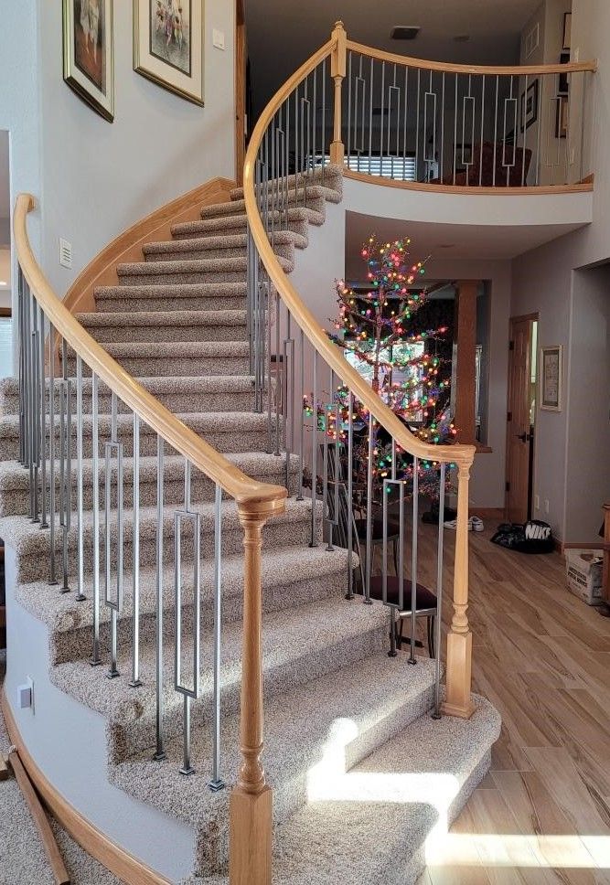 A curved staircase in a house with a christmas tree in the background