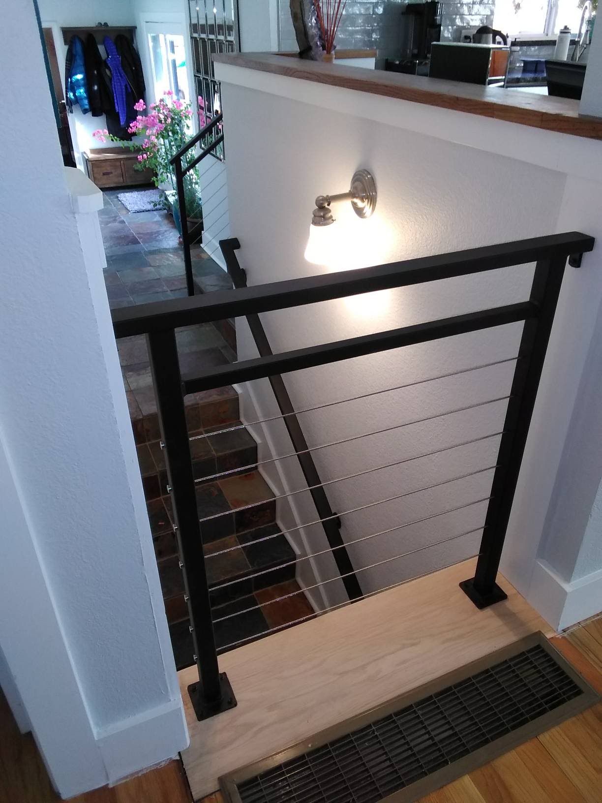 A staircase with a black railing and a light on the wall.