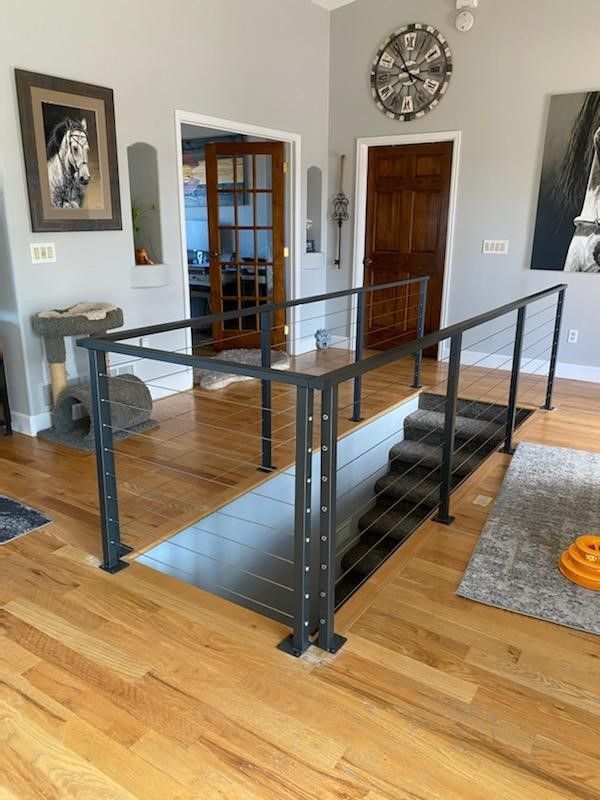 A living room with hardwood floors and a staircase with a metal railing.