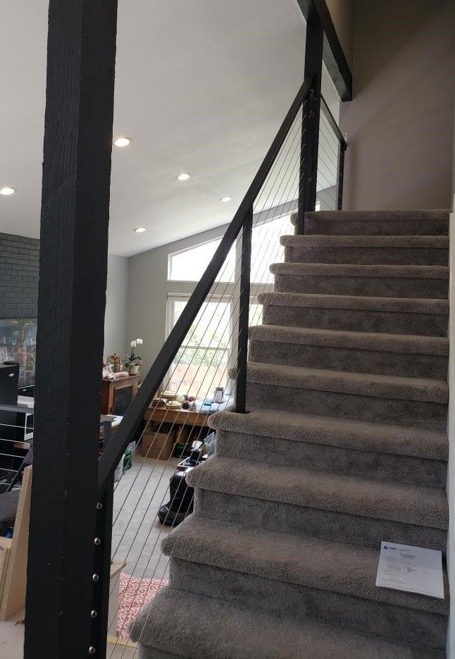 A staircase with carpeted steps and a black railing in a living room.