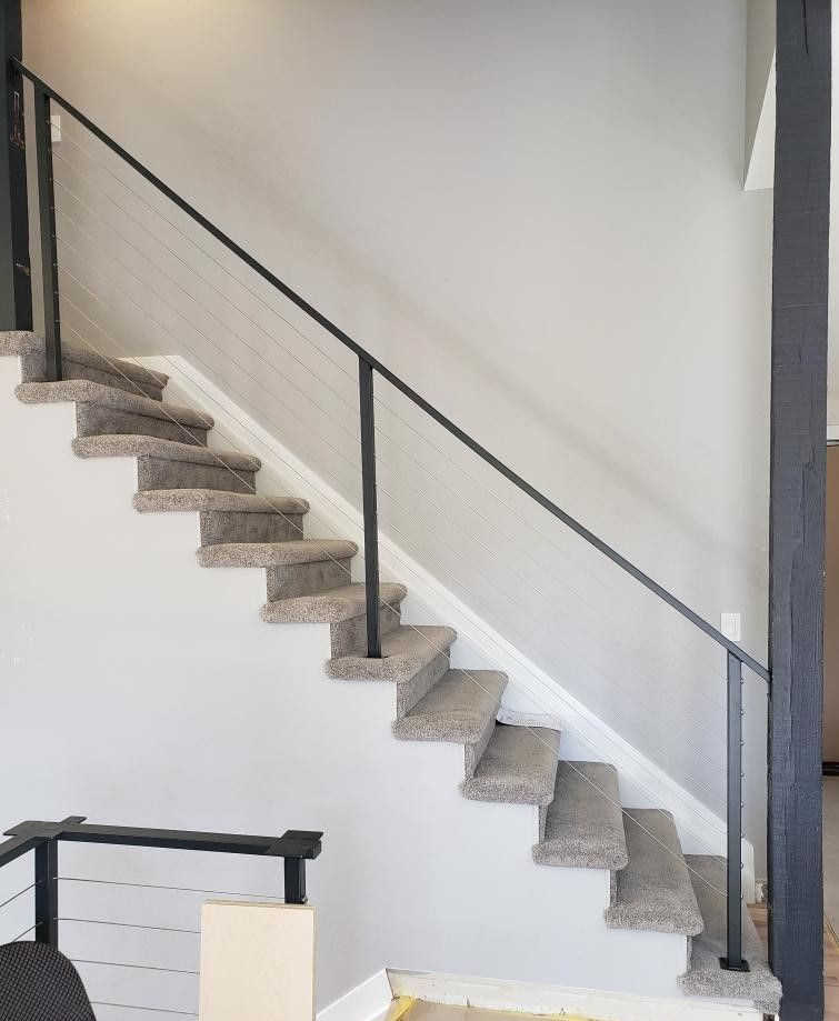 A staircase with carpeted steps and a black railing
