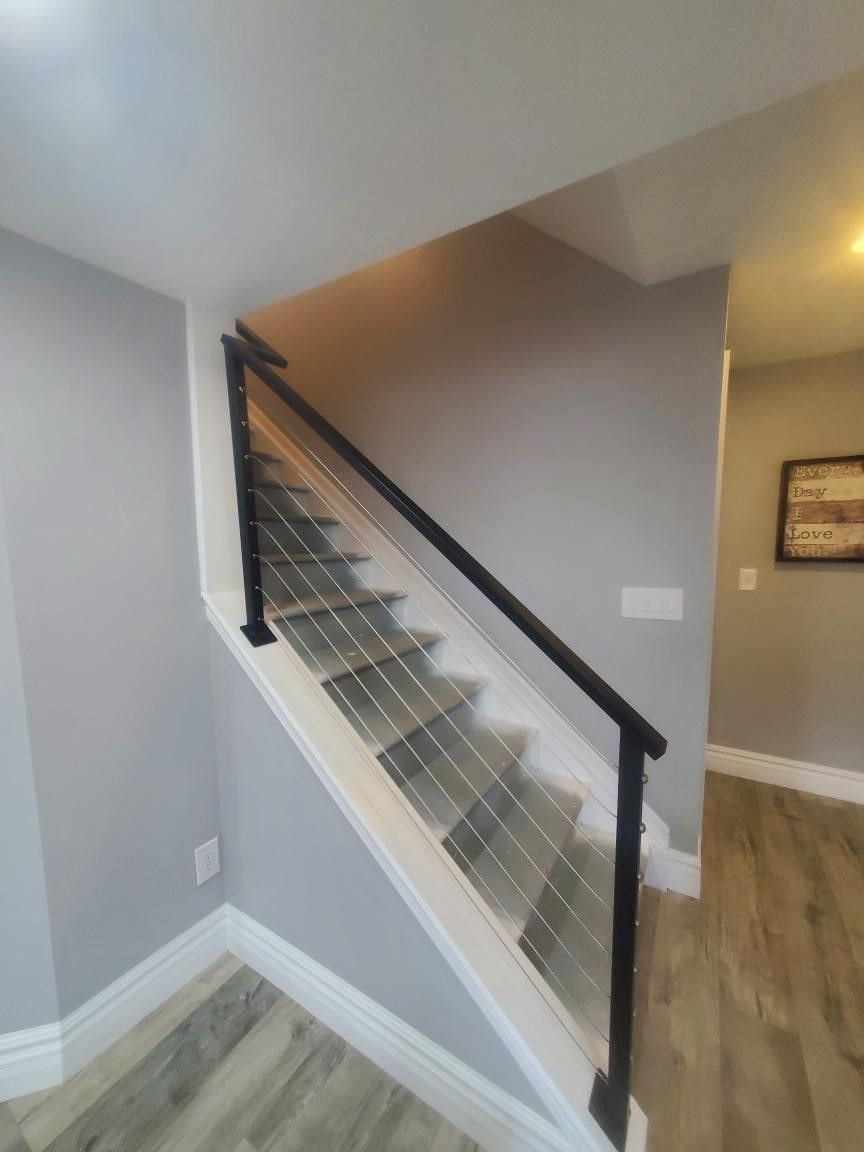 A staircase with a black railing and a picture on the wall