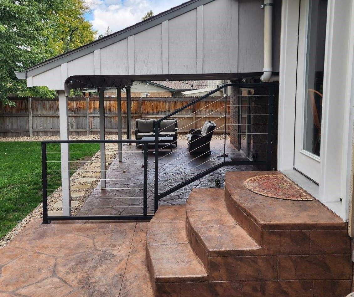 A patio with stairs leading up to it and a black railing