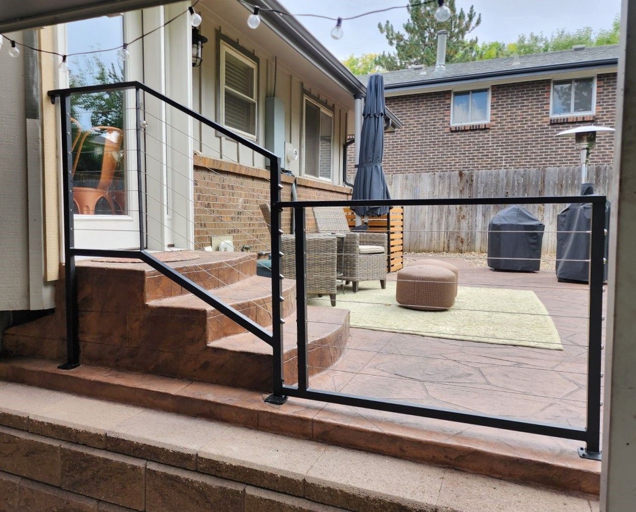 A patio with a black railing and stairs leading up to it.