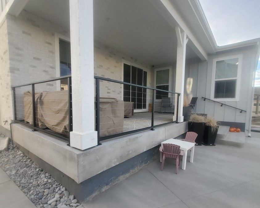 A porch with a railing and a table and chairs on it.