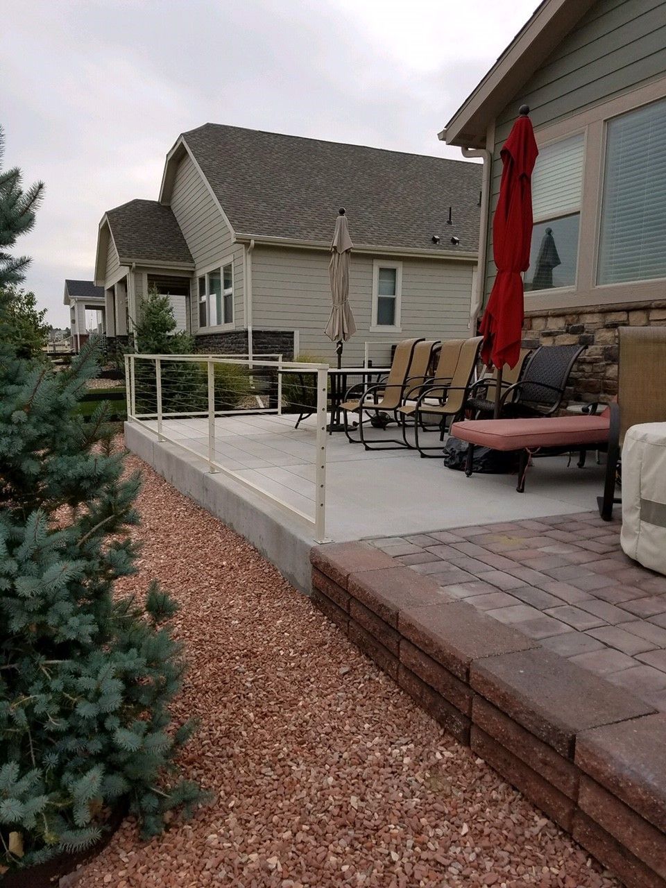 A patio with chairs and umbrellas in front of a house