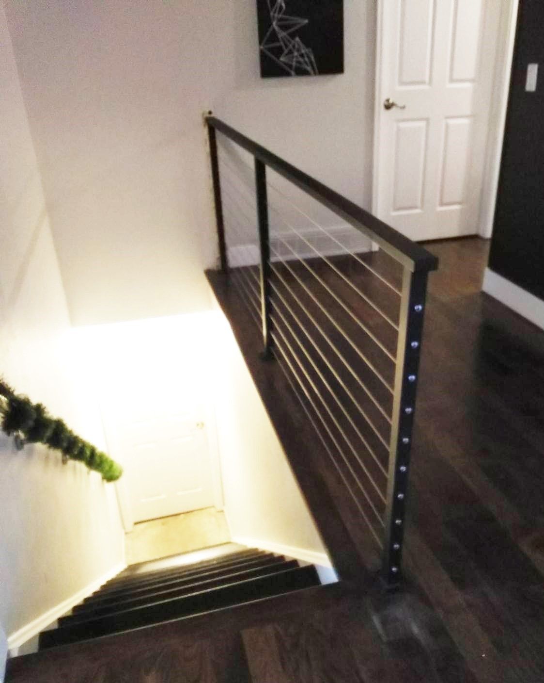 A staircase with a stainless steel railing and a painting on the wall