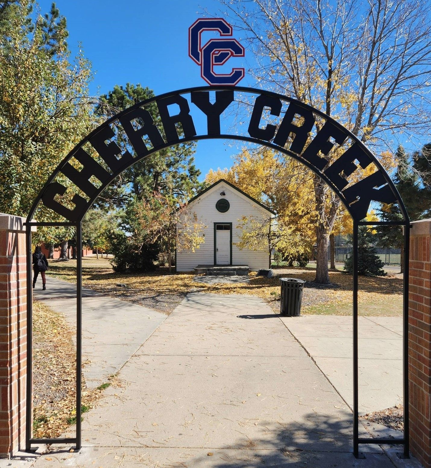 A sign for cherry creek with a white building in the background