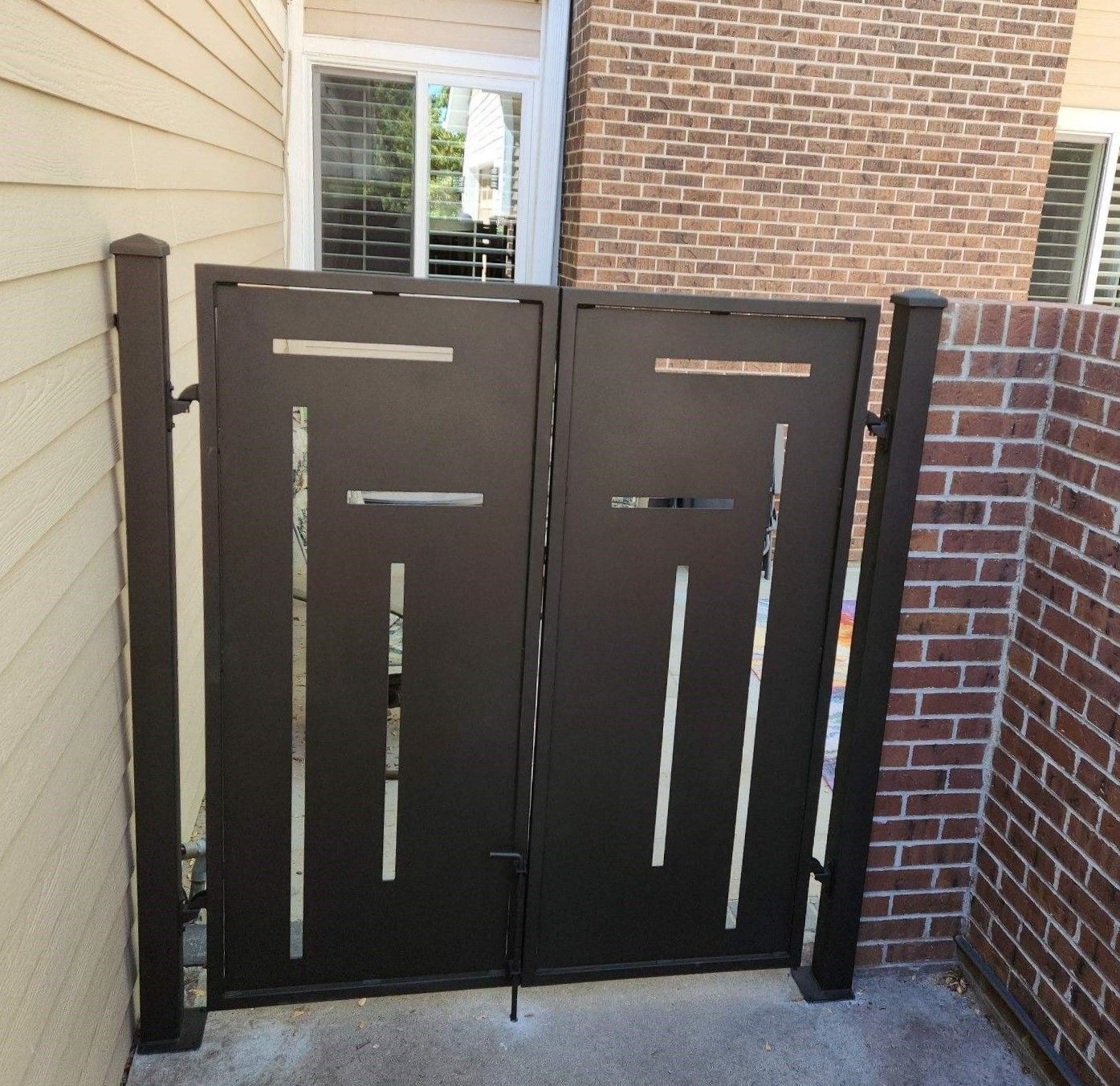 A black gate with a brick wall behind it
