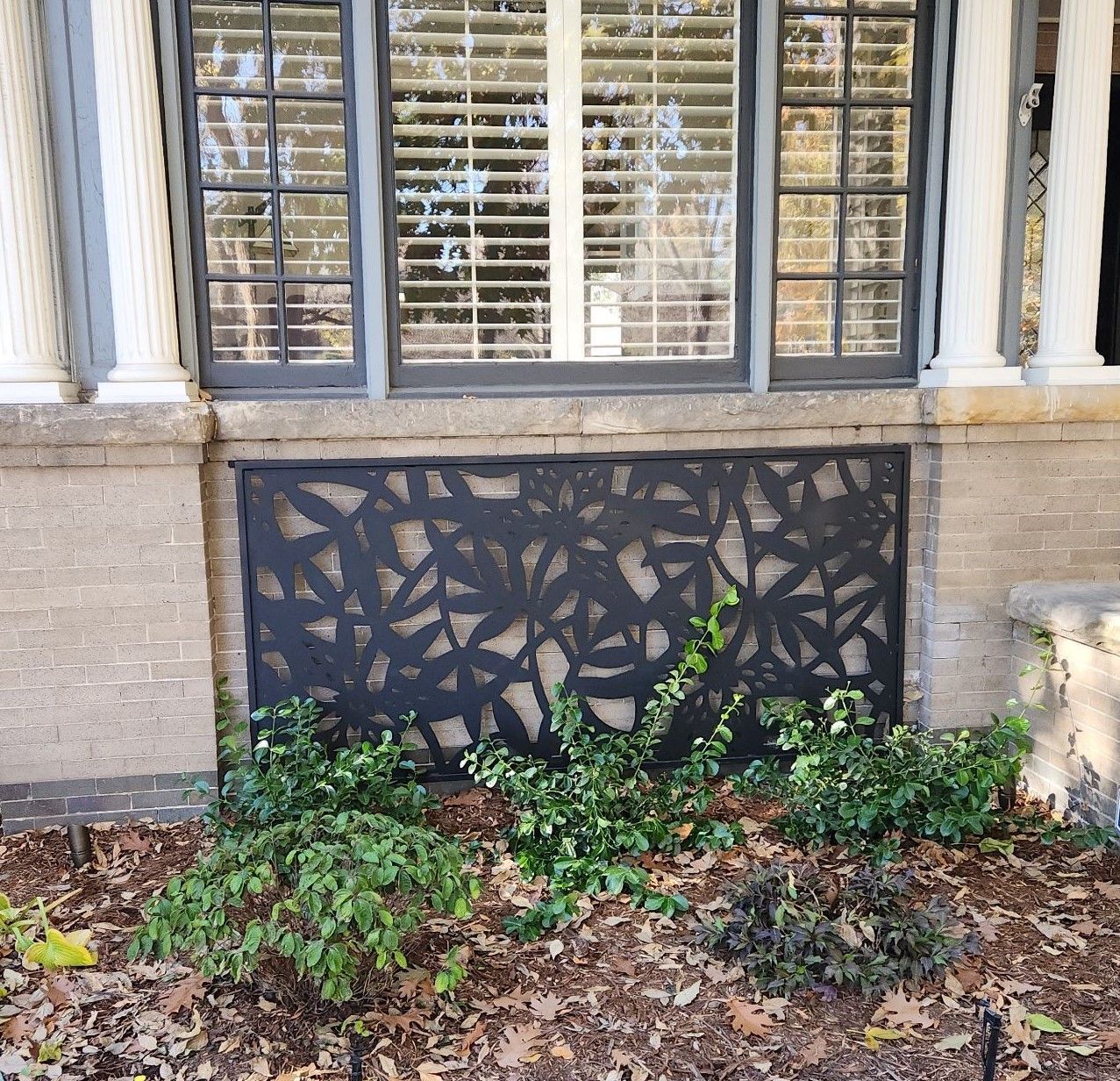 A brick building with a window and a shrub in front of it