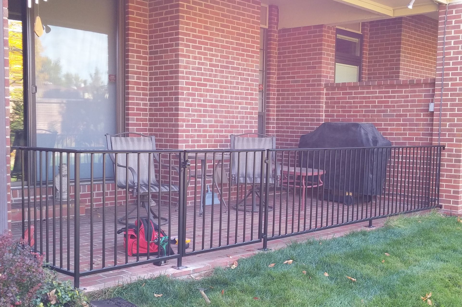 A brick house with a grill behind a metal fence.