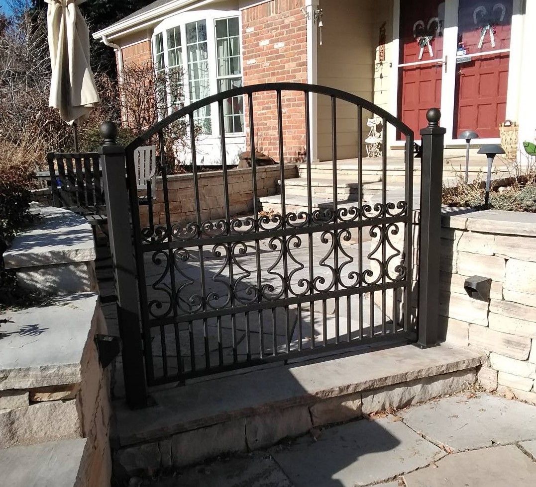 A wrought iron gate is in front of a brick house
