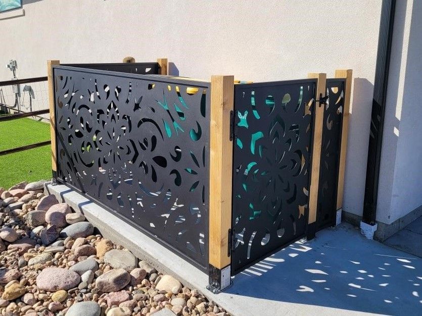 A black metal fence with a wooden frame is surrounded by rocks.