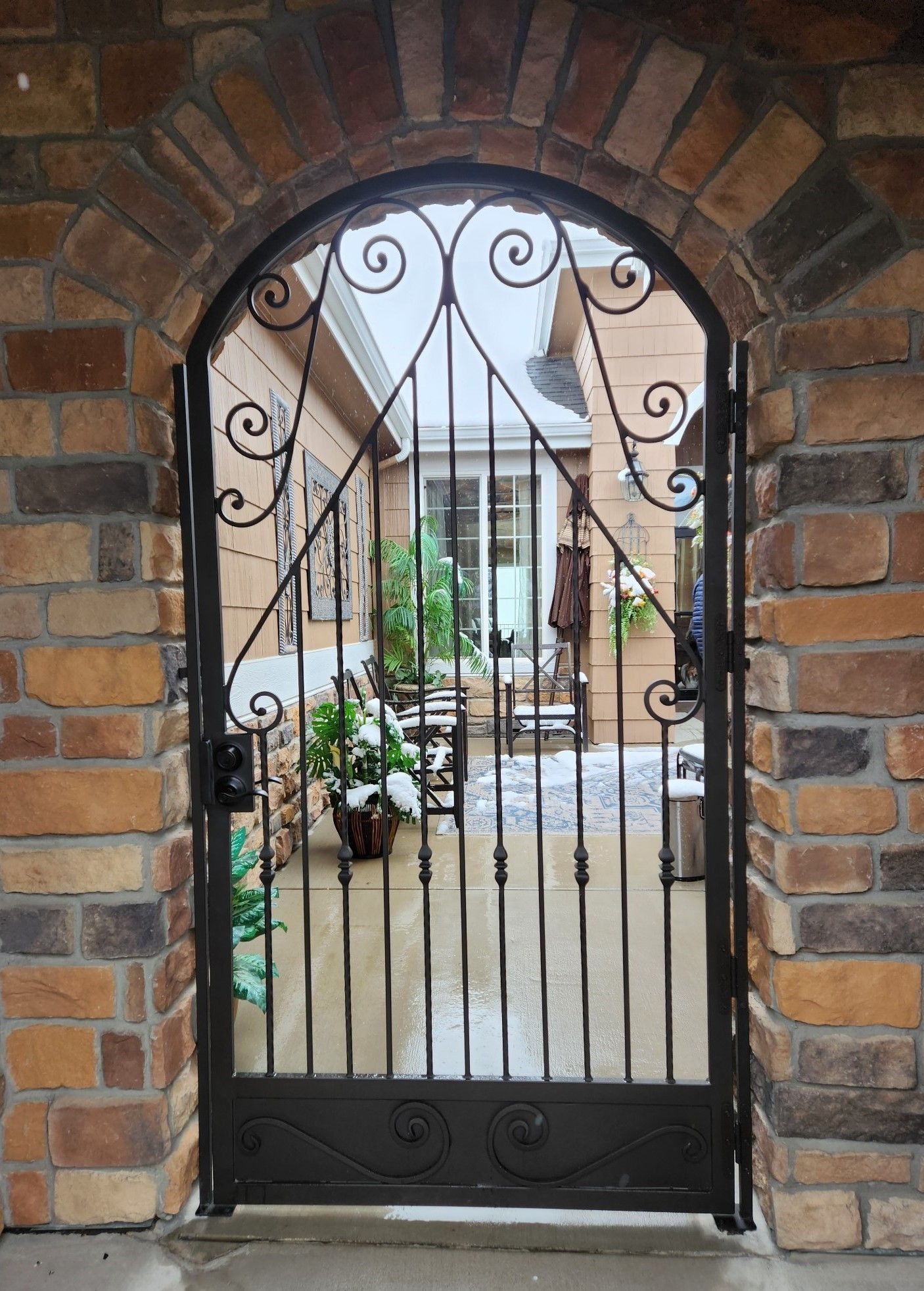 A wrought iron gate with a brick wall behind it