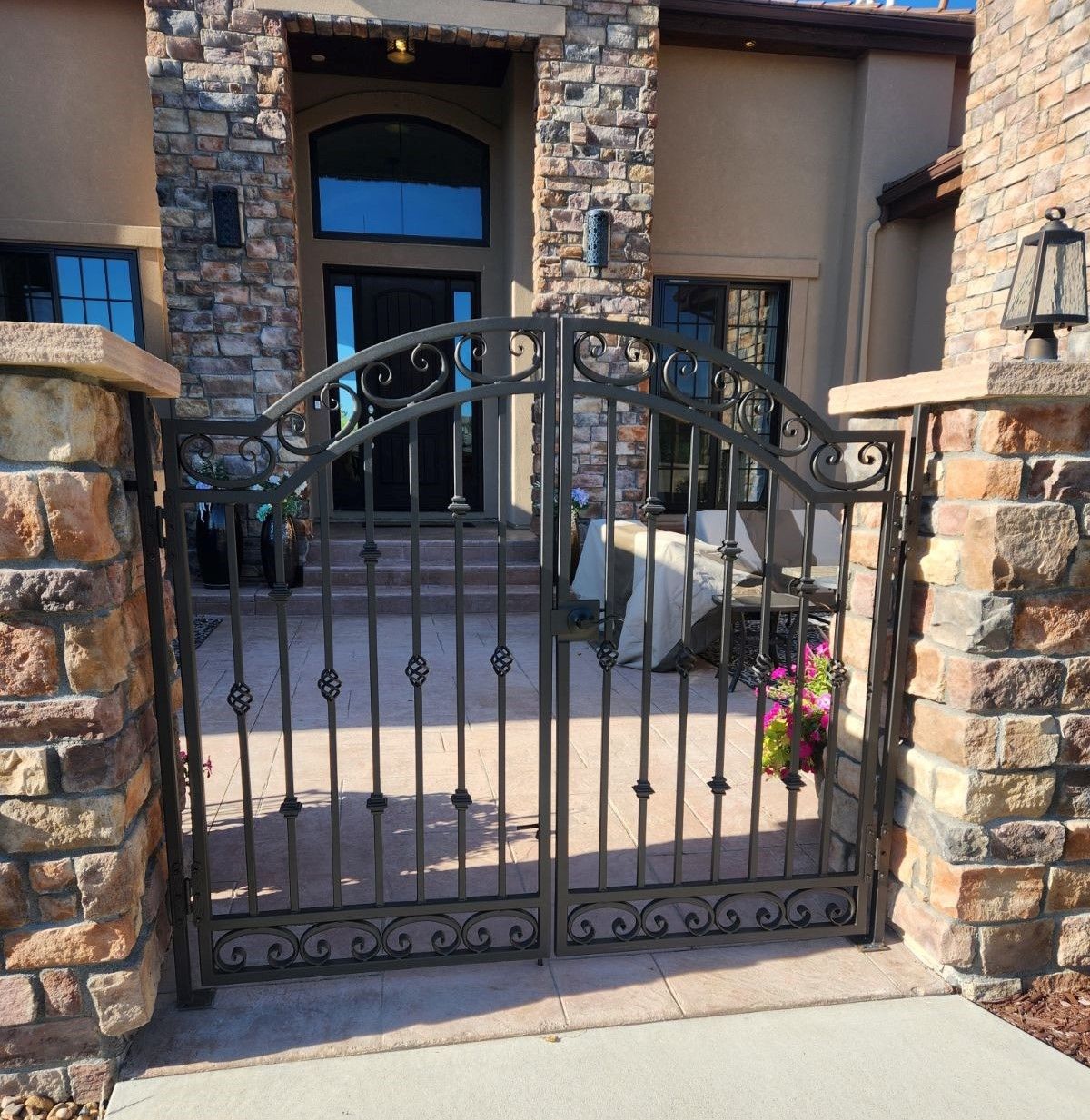 A wrought iron gate in front of a stone building