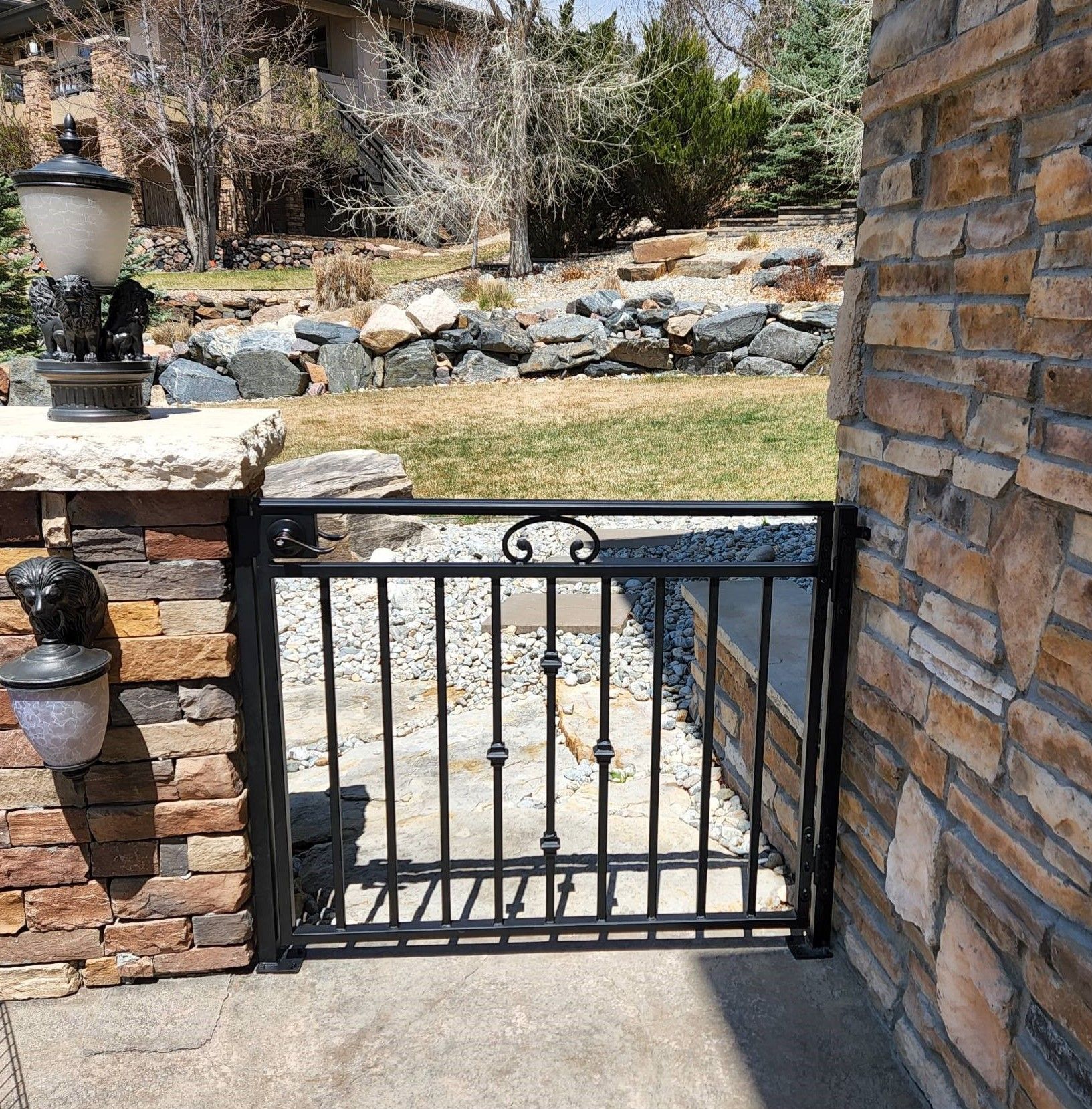 A wrought iron gate is sitting next to a stone wall.