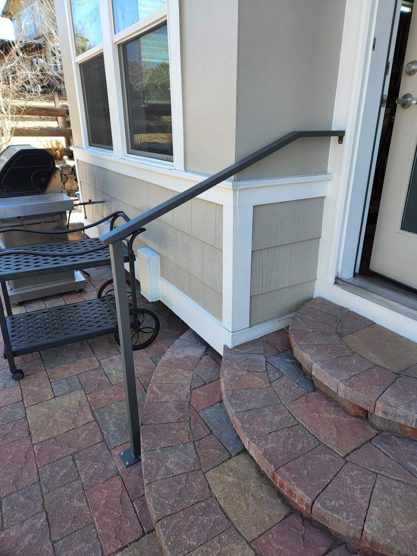 A metal railing on a brick patio next to a house.