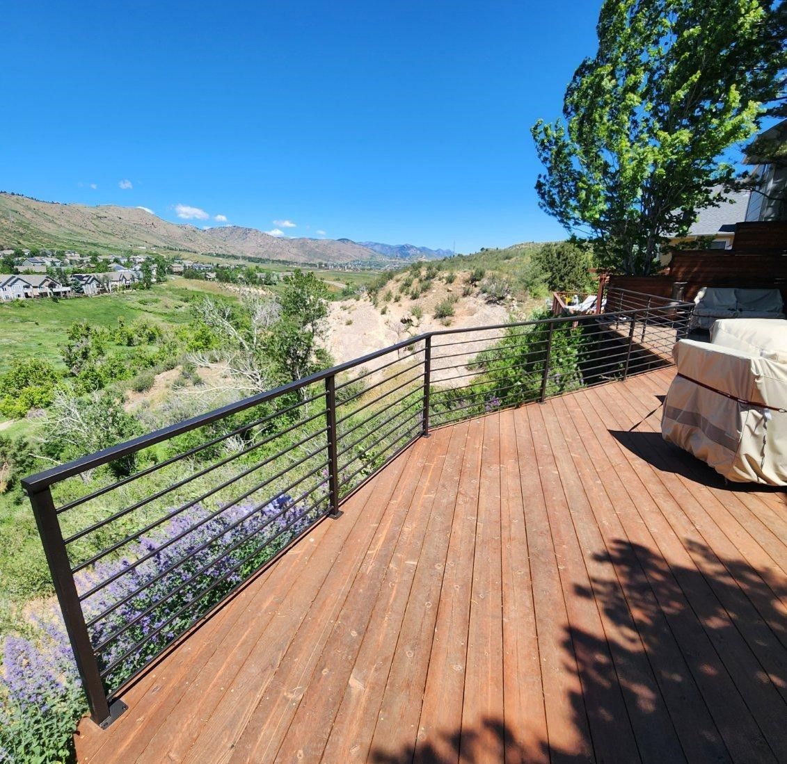 A wooden deck with a view of a valley and mountains.