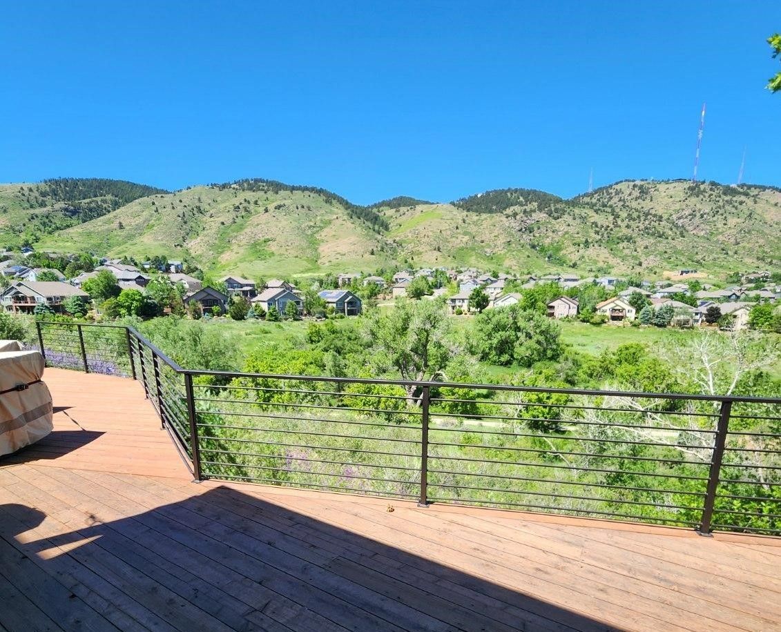 A view of a mountain range from a deck with a railing.