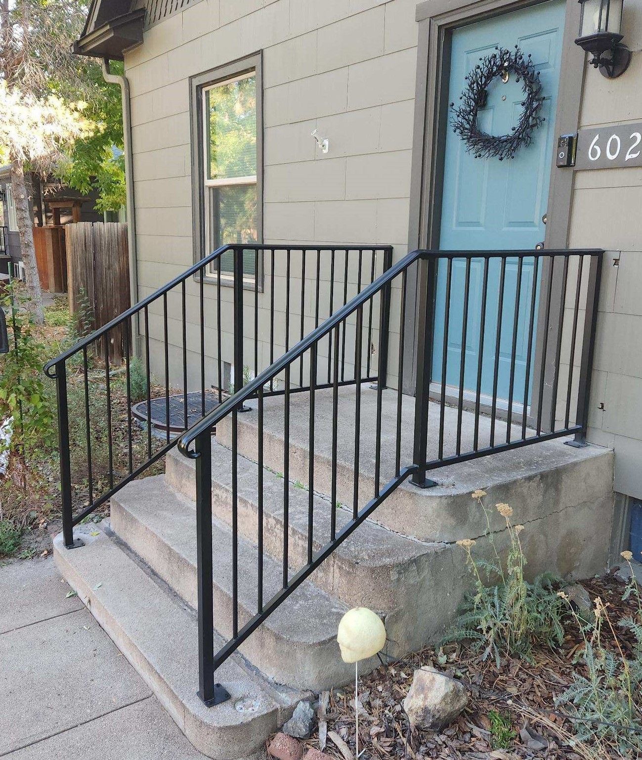 A house with a blue door and a black railing on the porch.