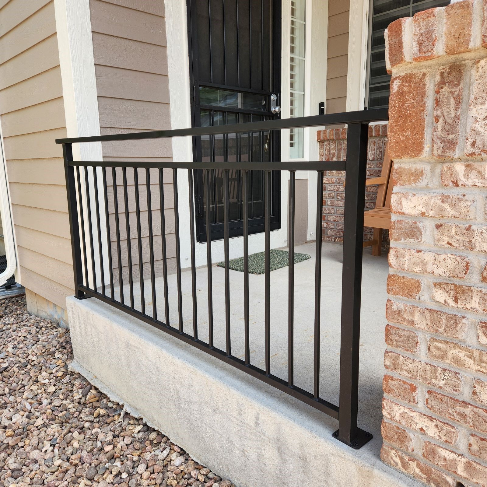 A porch with a black railing and a black door