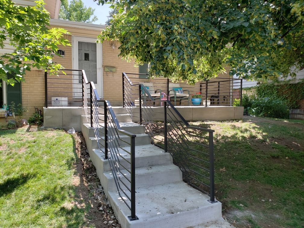 A staircase leading up to a deck with a railing in front of a house.