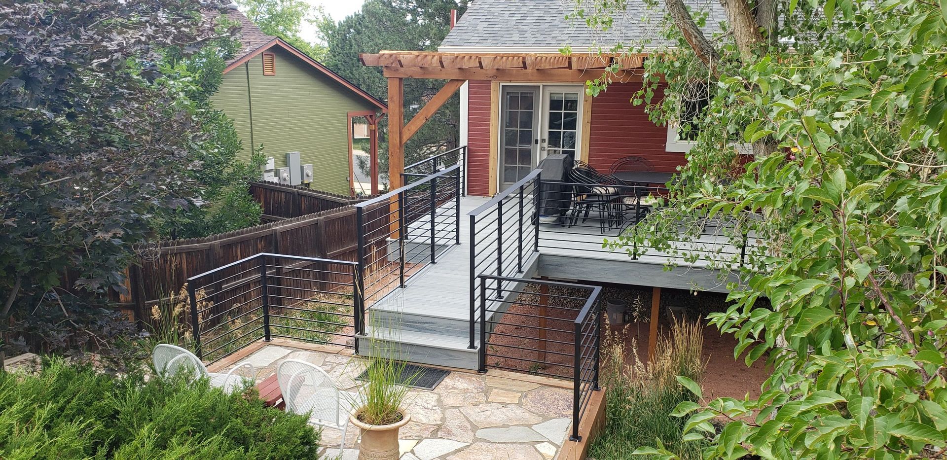 A red house with a deck and a pergola in the backyard.