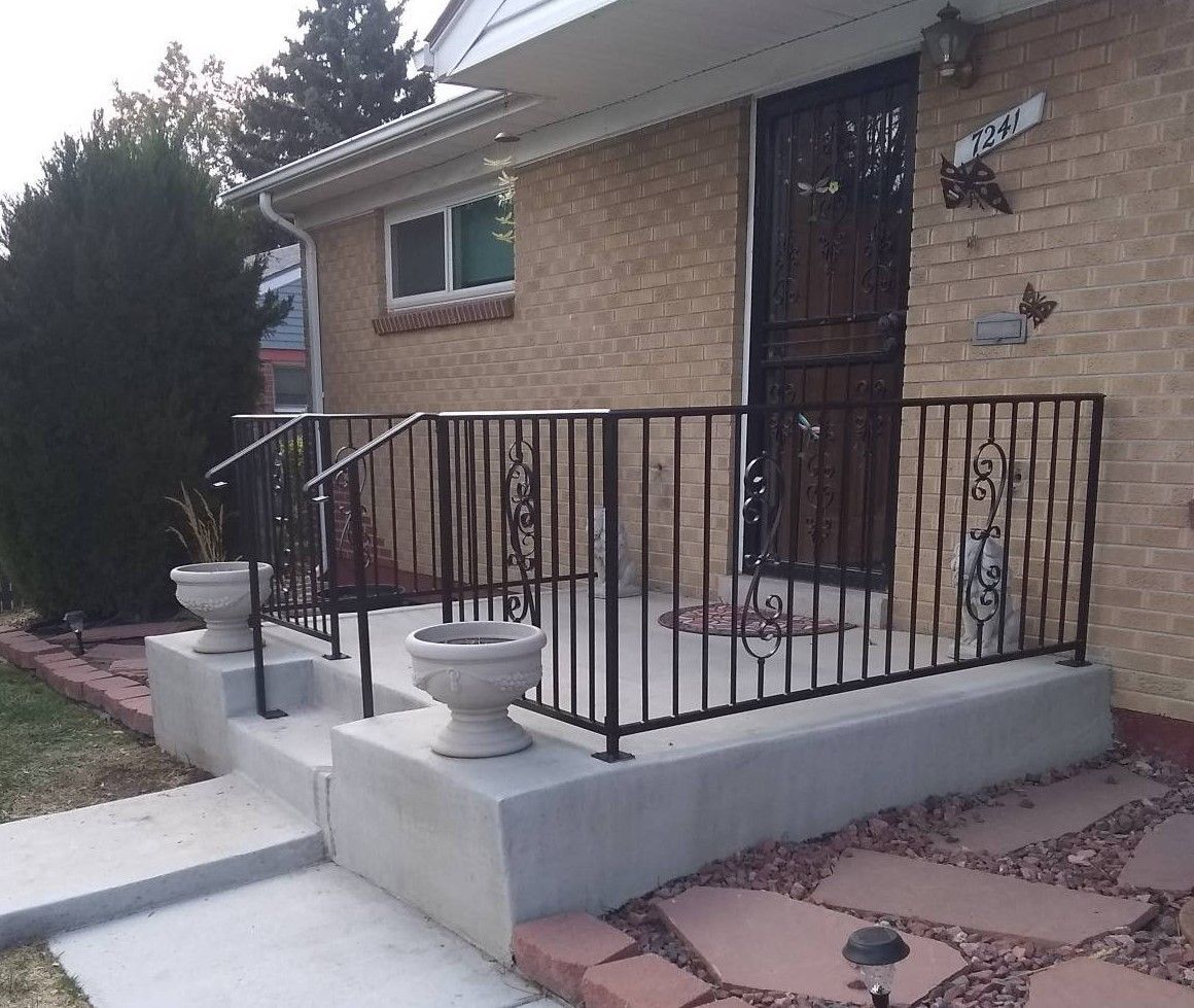 A brick house with a wrought iron railing on the porch