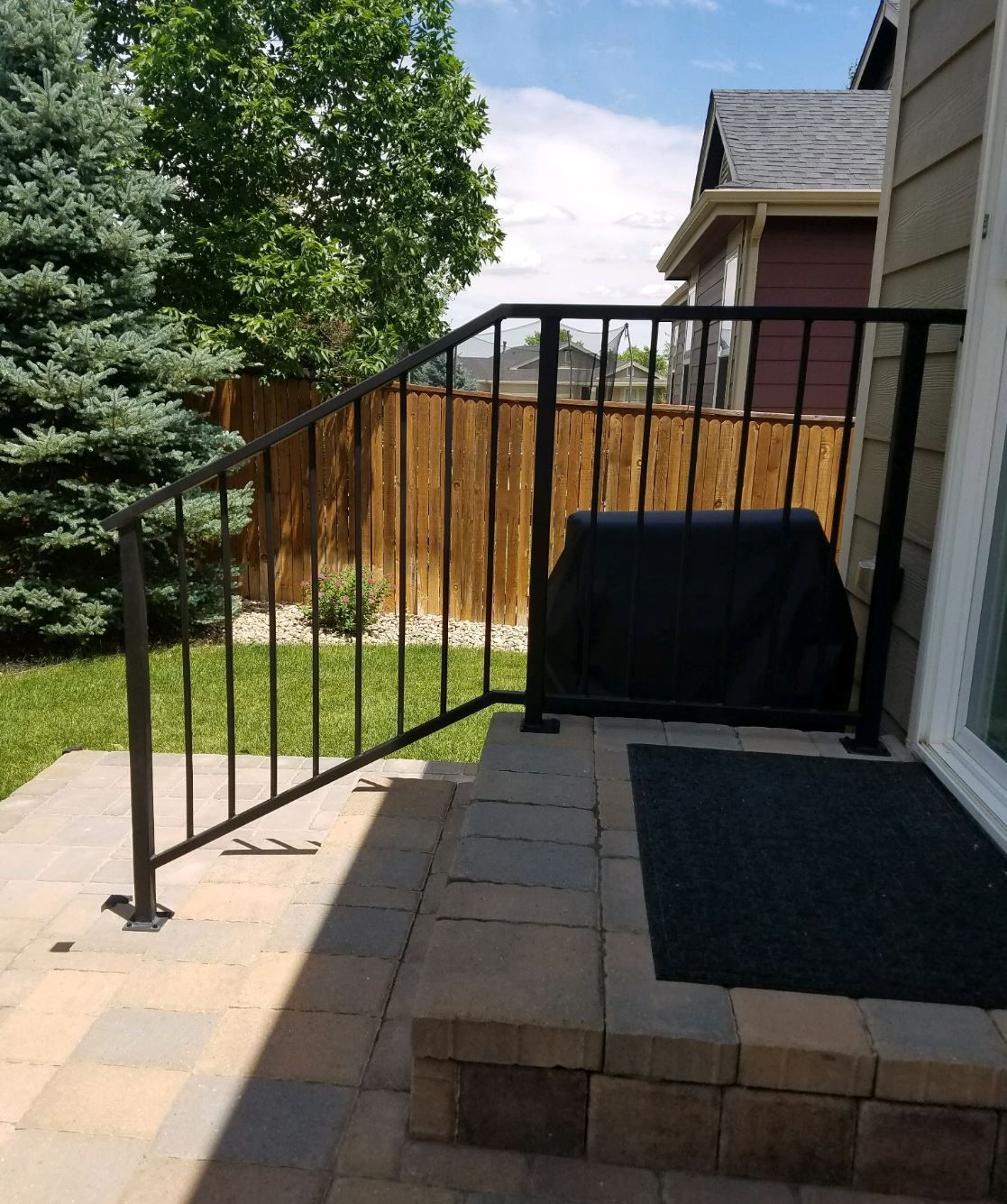 A porch with a black railing and a grill on it
