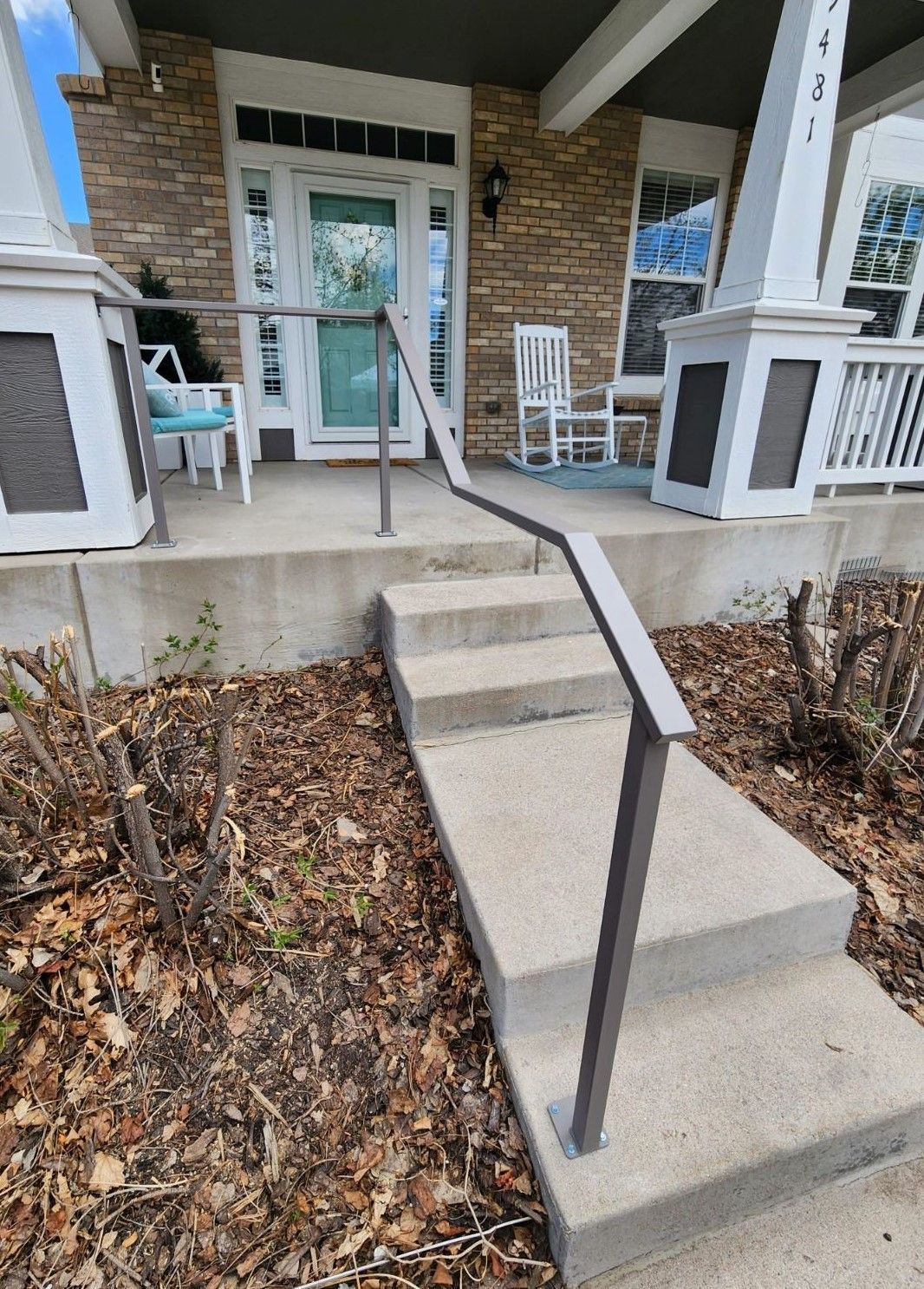 A staircase leading up to a porch with a railing and rocking chairs.