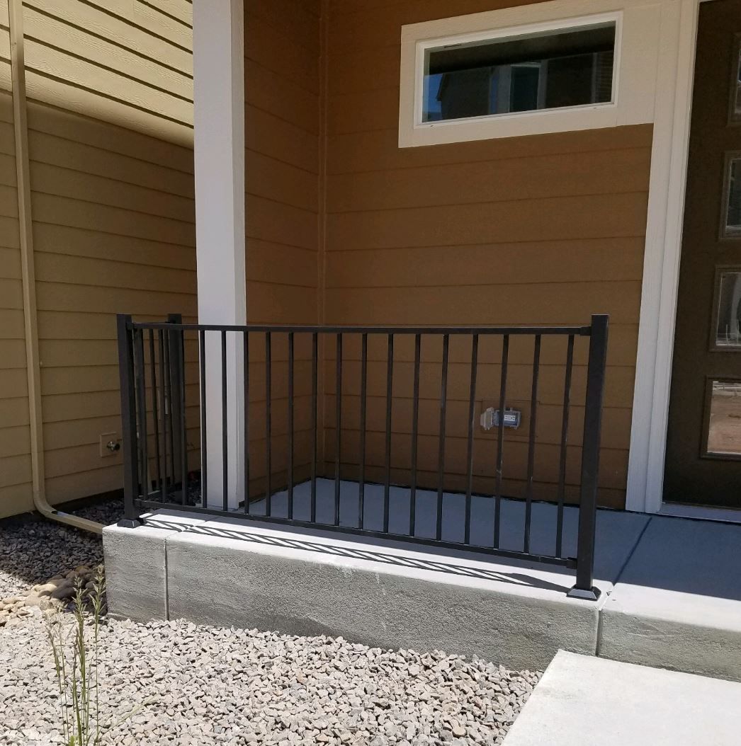 A porch with a metal railing and a ramp leading to the door.