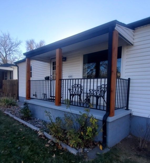 A white house with a porch and chairs on it