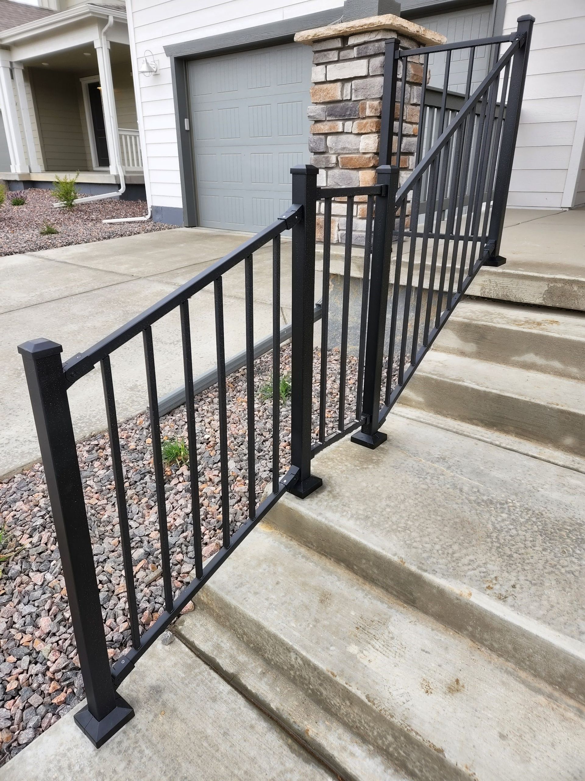 A black railing on a set of stairs in front of a house.