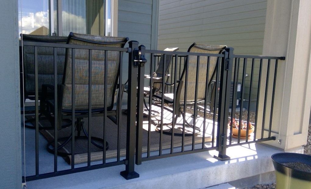 A black fence surrounds a patio with chairs and a table.